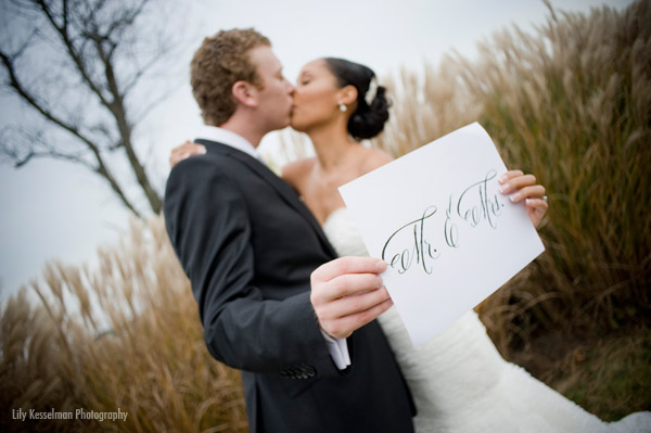 Newlyweds share a kiss while holding a Mr & Mrs sign