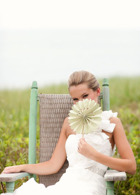 Bride in a wedding dress holding a flower fan, smiling in nature