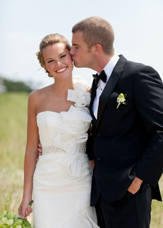 A happy couple on their wedding day, groom kissing the bride