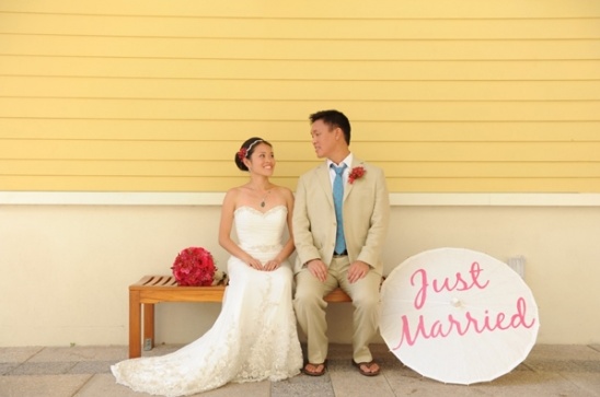 Newlyweds smiling together on a bench with a Just Married sign