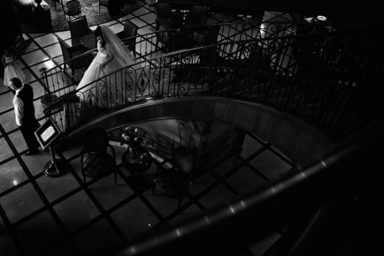 Bride descending ornate staircase in elegant black and white photo
