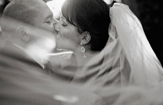 Romantic black and white photo of a kissing bride and groom