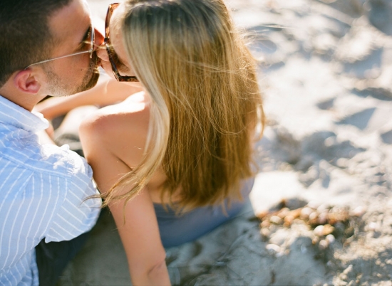 Couple kissing on the beach, enjoying a romantic moment in the sunlight
