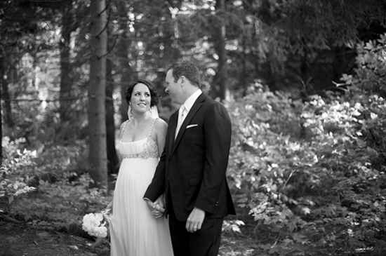 Bride and groom holding hands in a black and white forest wedding