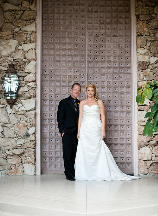 Happy couple posing on their wedding day in front of a door