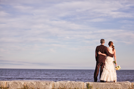 Bride and groom gaze at the sea on their wedding day