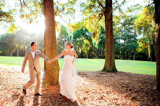 Wedding couple holding hands walking through a sunny forest