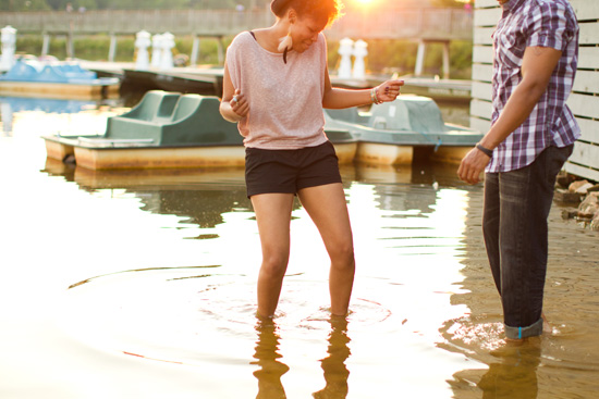 A woman dances in the water as the sun sets with a man nearby