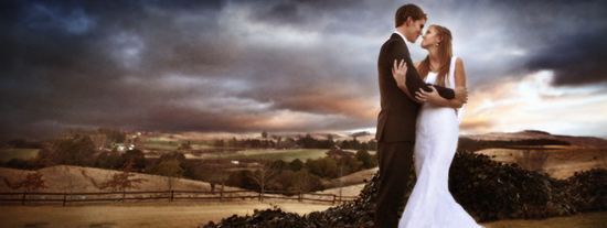 Newlyweds embrace on a scenic landscape during a stormy sunset