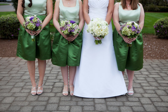 Bride with bridesmaids in green dresses holding flower bouquets