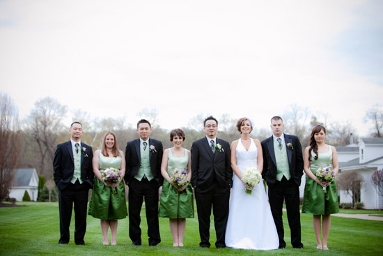 Wedding party posing on green grass with bride and groom center