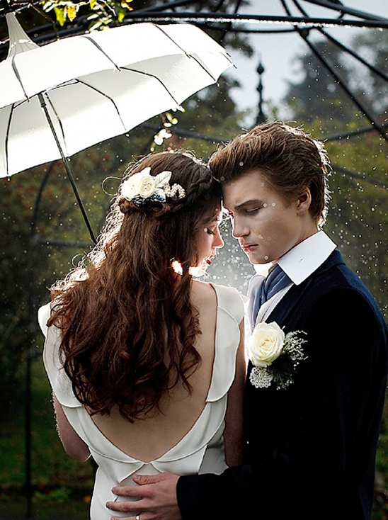 Romantic couple under a white umbrella in the rain at their wedding