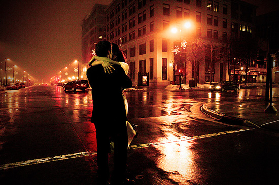 Couple embraces on a city street at night, romantic scene