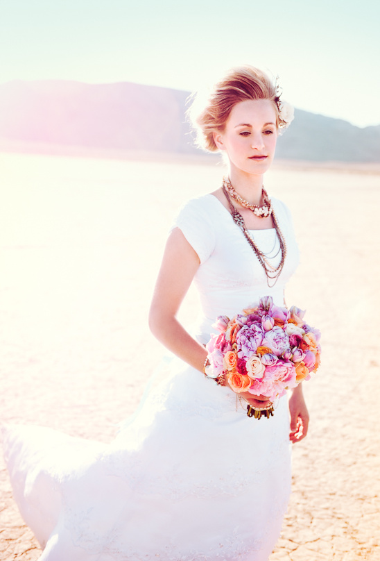 Bride in white dress holding floral bouquet outdoor