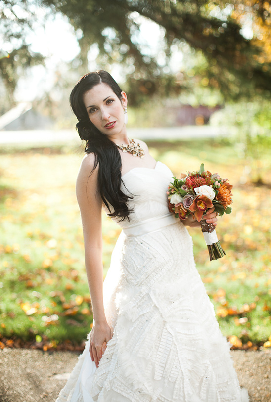 Bride in white gown with bouquet in autumn setting