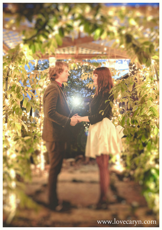 Couple holding hands under a lighted garden archway