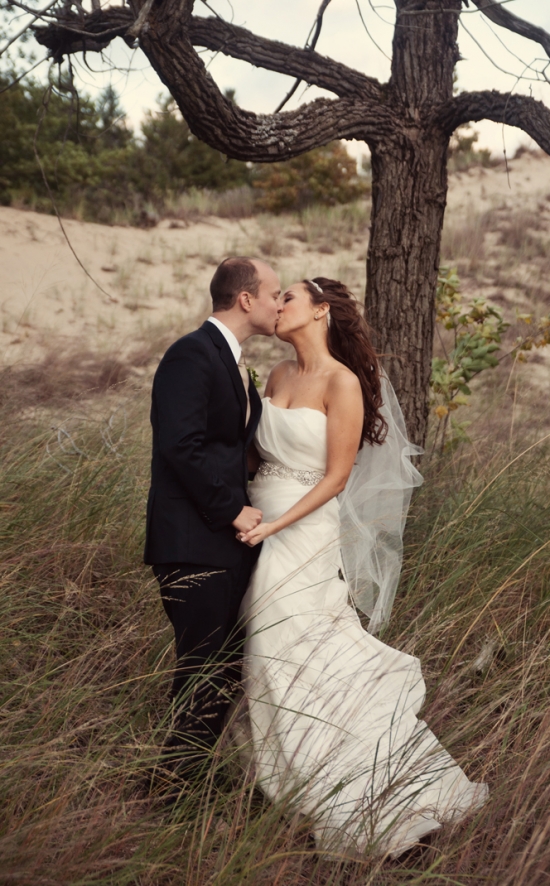 Bride and groom kissing in grassy field