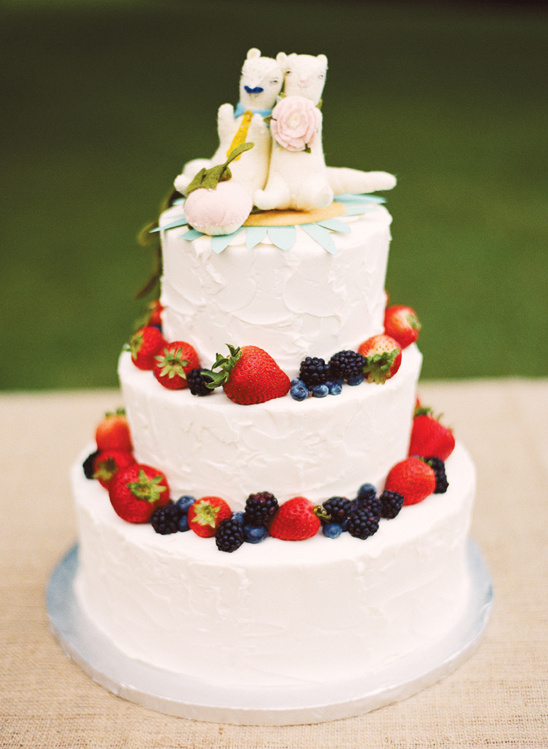 Three tier wedding cake with berry and llama toppers