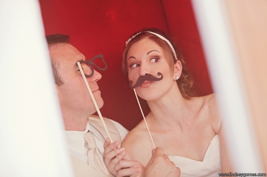 Bride and groom play with props in a photo booth