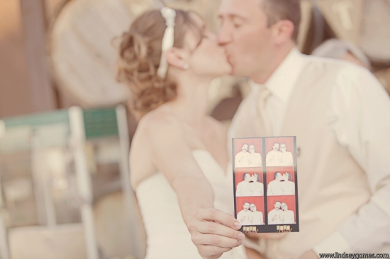 Bride and groom kissing holding photobooth strip