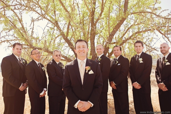 Groom and groomsmen in black suits under a tree