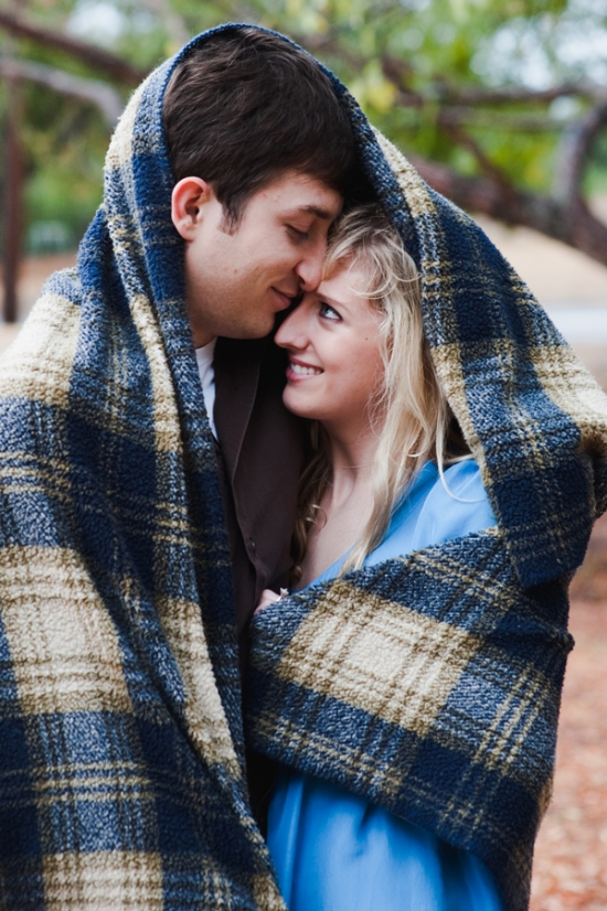 Romantic couple cuddled under a plaid blanket