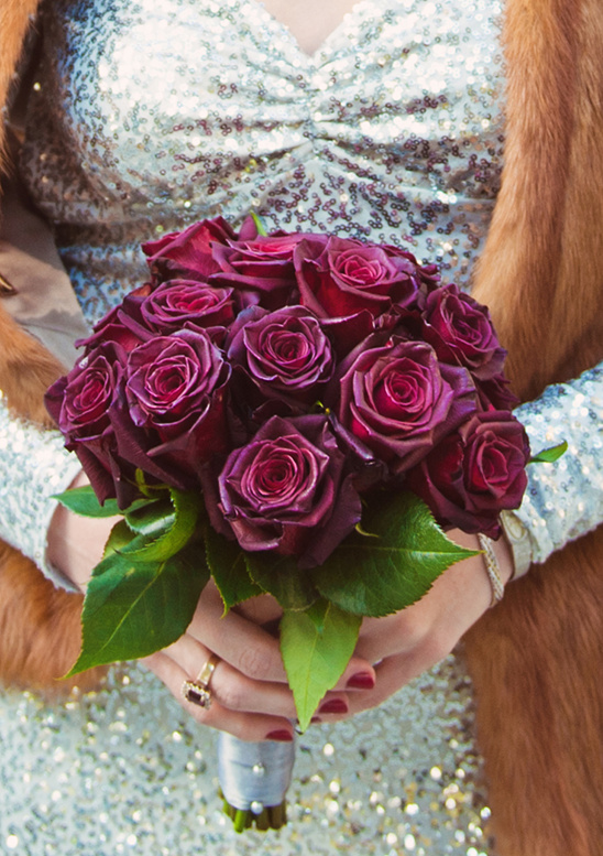 Bride holds a bouquet of dark red roses at wedding