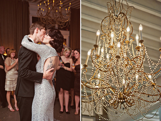 Newlyweds kiss under an elegant chandelier at their wedding