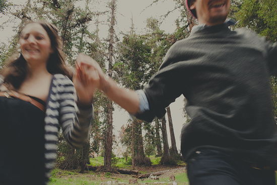 Couple running through woods, happy together