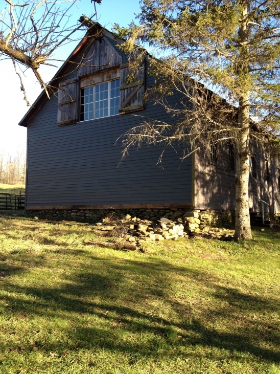Weathered gray barn with window on a grassy field