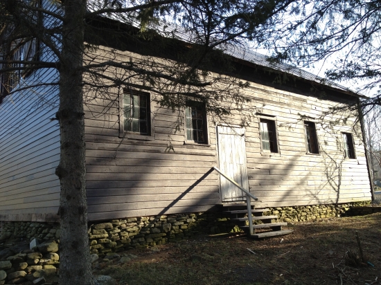 Historic weathered wooden building with stone foundation