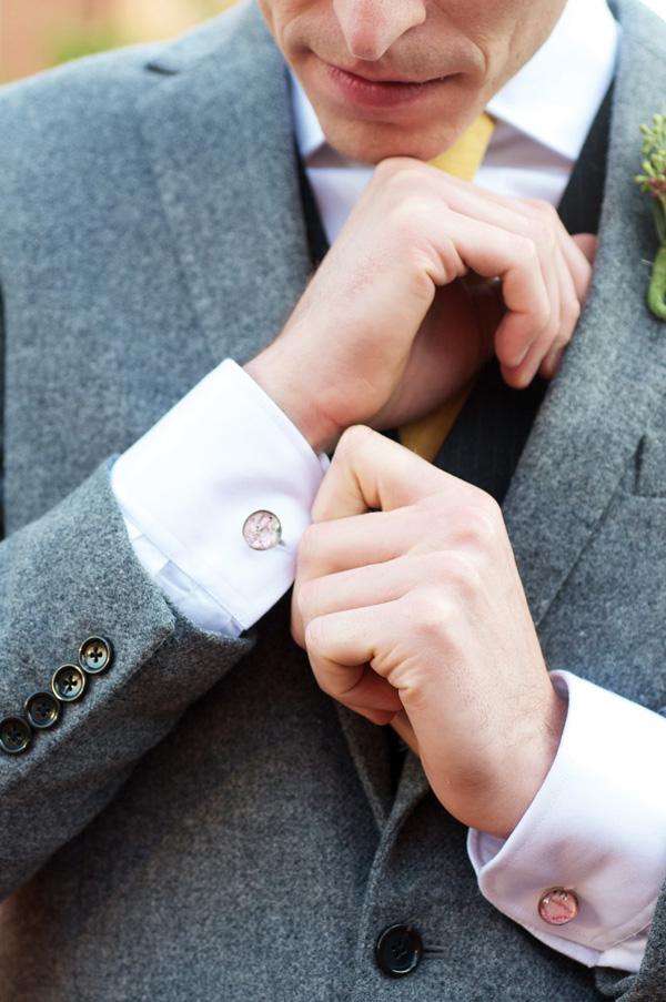 Man in gray suit adjusting cufflinks