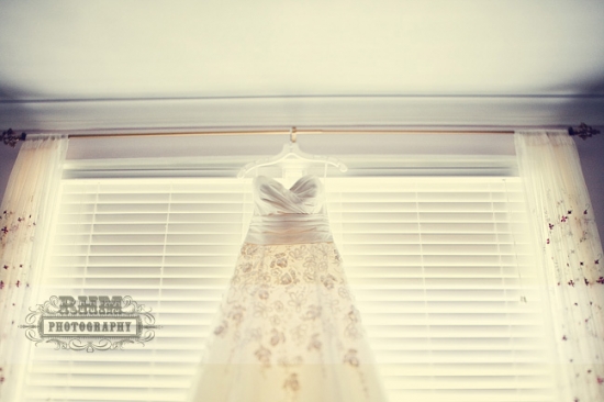 Elegant wedding gown hanging by window
