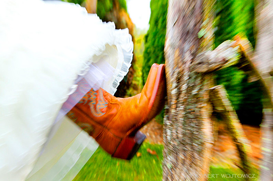 Bride's orange cowboy boot kicks up near tree