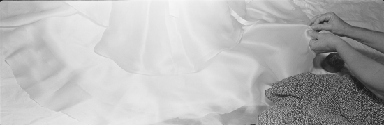 Hands carefully adjusting a white silk wedding dress