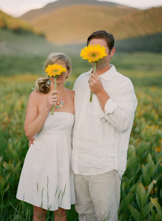 Couple hides faces with sunflowers in field