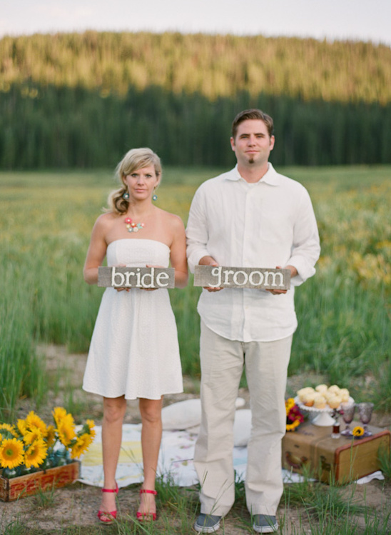 Bride and groom holding signs in field