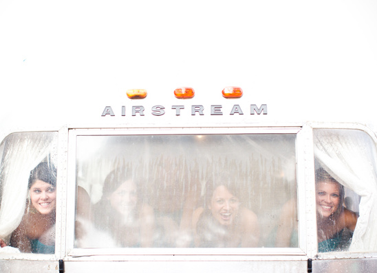 Bridesmaids peek from a steamy Airstream window
