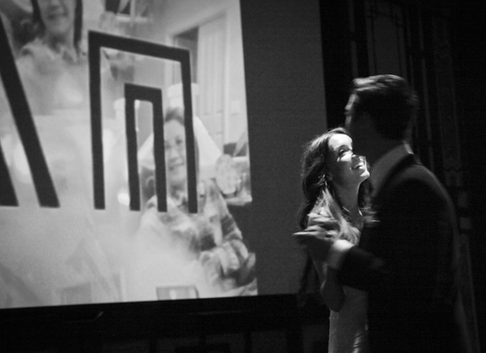 Couple dancing joyfully,  black and white photo projected behind