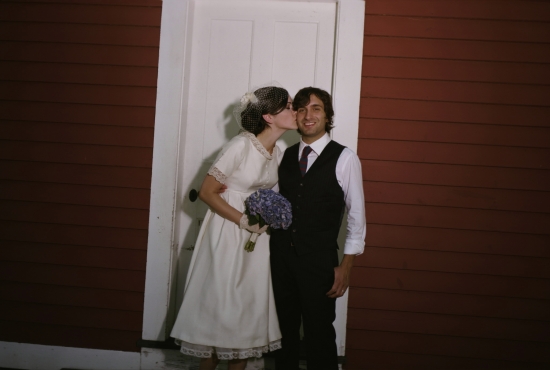 Bride kisses groom on his cheek during wedding photo