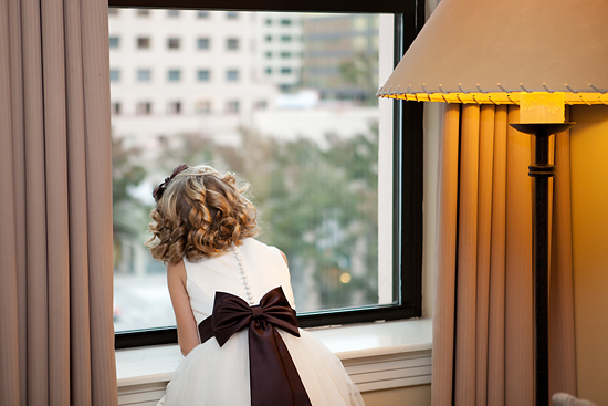 Girl in dress looking out window at city