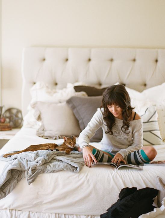 Woman relaxing in bed, reading with her cat