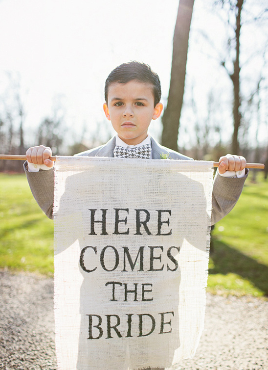 Ring bearer holds Here Comes the Bride wedding sign