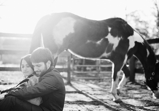 Couple embracing next to a horse on a farm in grayscale