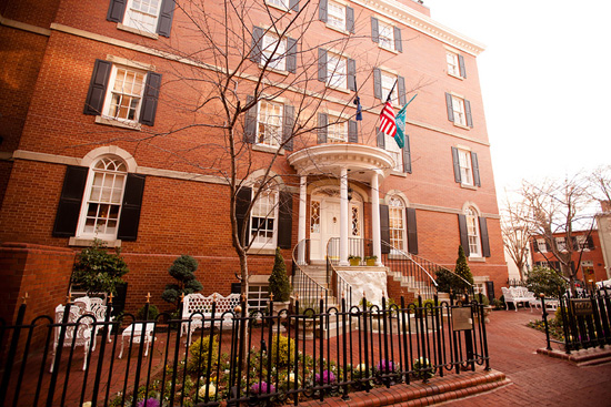 Historic brick building with a white portico and flags