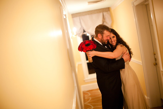 Bride and groom embrace with red roses at wedding