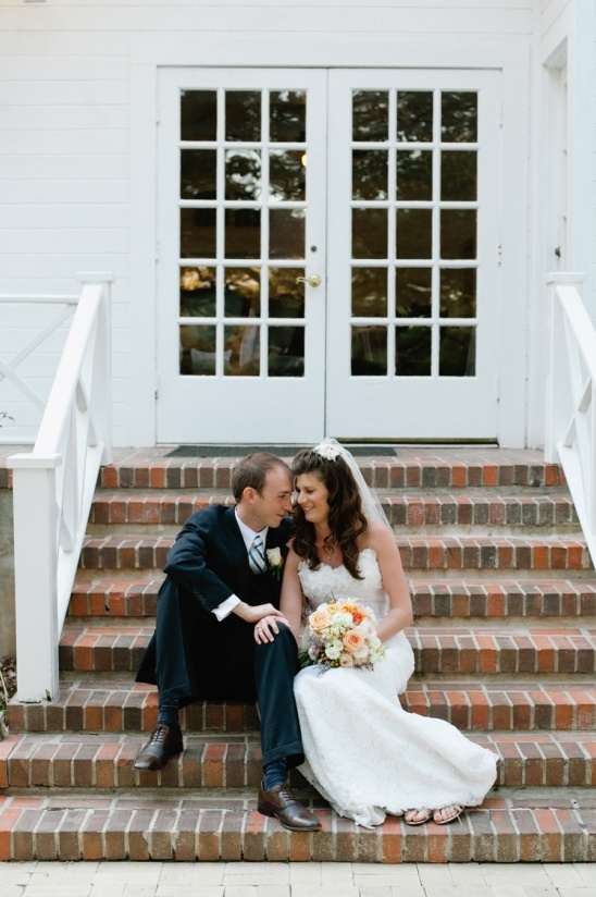 Bride and groom sit on steps on wedding day