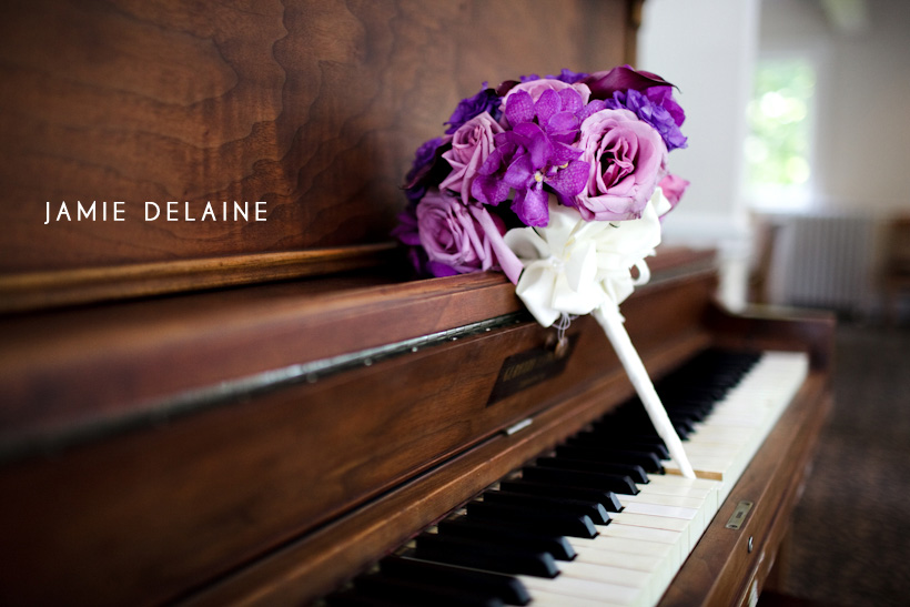 Purple bridal bouquet rests on a vintage piano keyboard