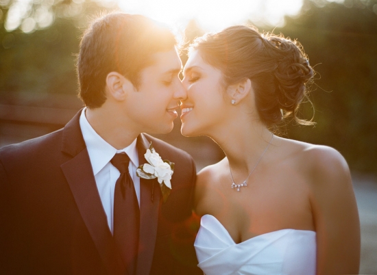 Bride and groom sharing a kiss at their sunny wedding