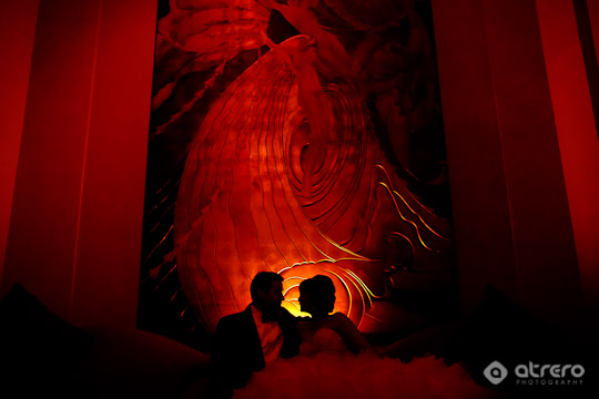 Silhouette of a couple against a red art piece